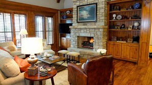 Una sala de estar acogedora con chimenea de piedra, estanterías de madera y asientos cómodos.
