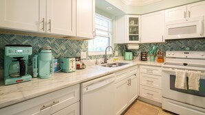 A kitchen with white cabinets, a microwave, a coffee maker, and a dishwasher.