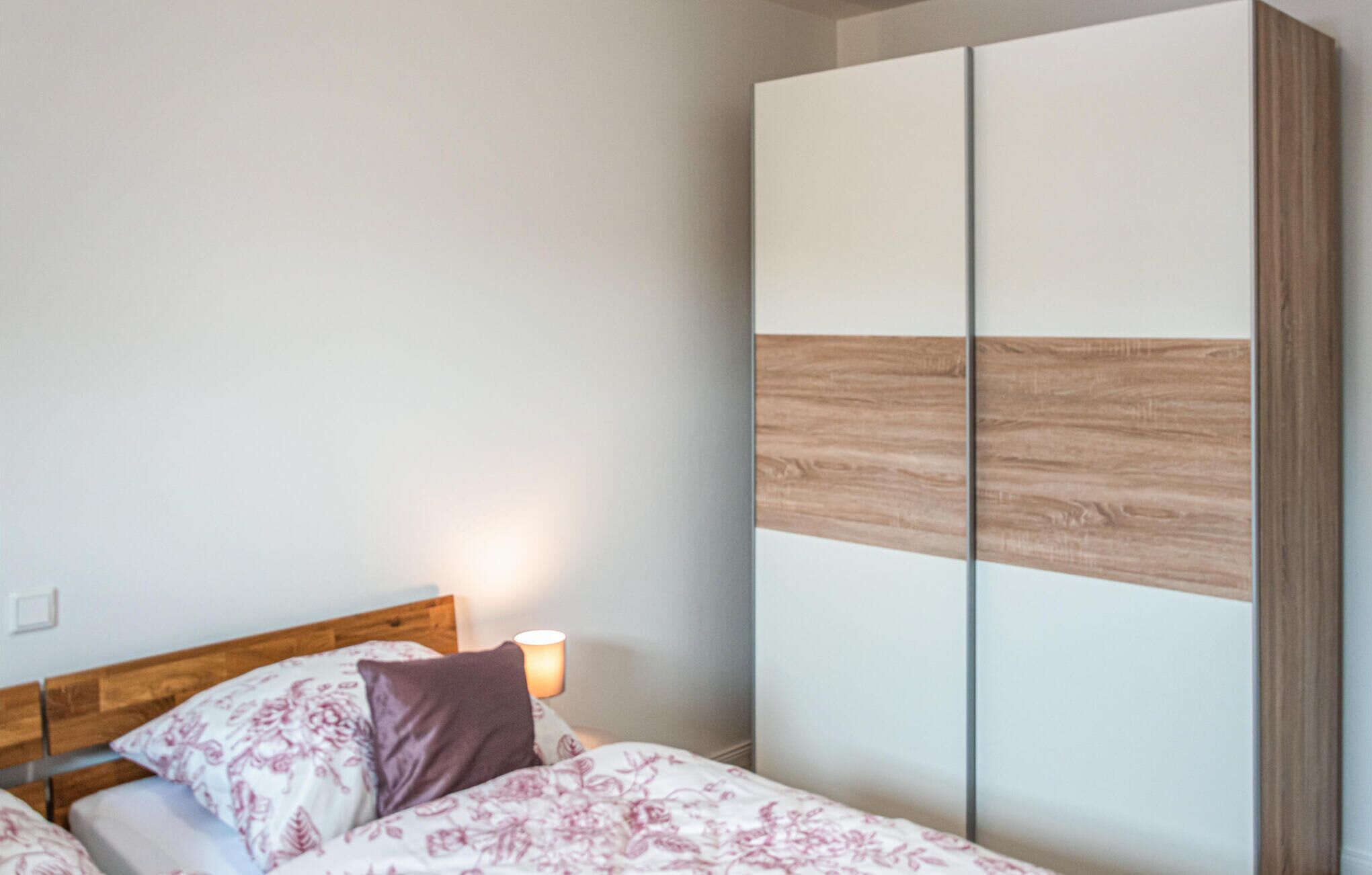 A bedroom with a bed, a nightstand, and a wardrobe.