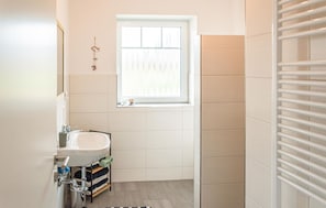 Bathroom features a sink, window, towel rack, and shelf.