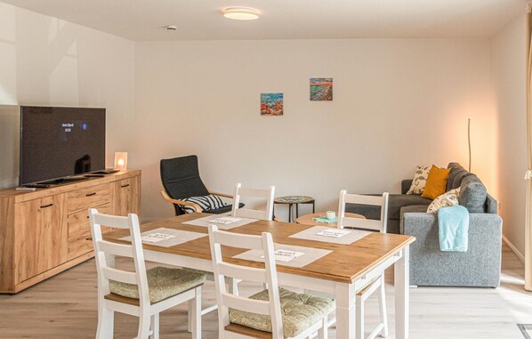 Cozy living space with a dining table, flat-screen TV, and comfortable sofa.
