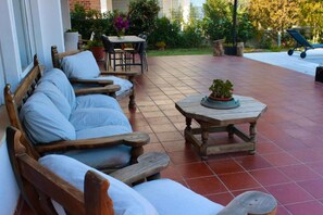 Une terrasse dotée de mobilier en bois, notamment des canapés et une table, ainsi que d’une plante en pot.