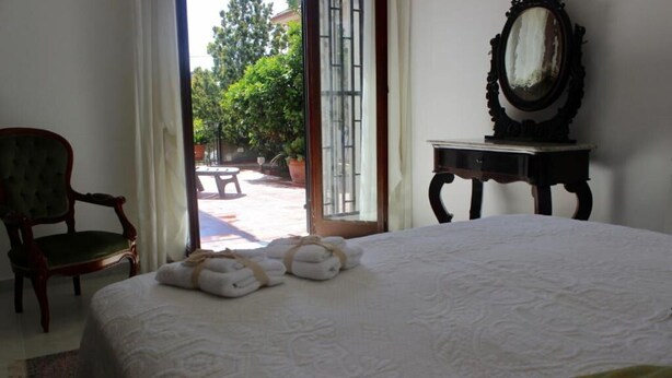 Una camera d'albergo con un letto, una sedia, un tavolo e una finestra vista esterna.