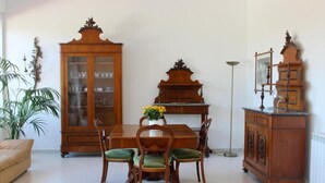 Zona pranzo con tavolo e sedie in legno, un mobile con ante in vetro e una lampada da terra.