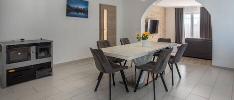 Un espace repas moderne avec une table blanche, des chaises grises et un four encastré.