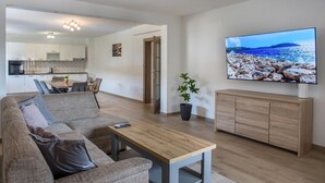 En moderne stue med sofa, sofabord og fjernsyn på et træskab.