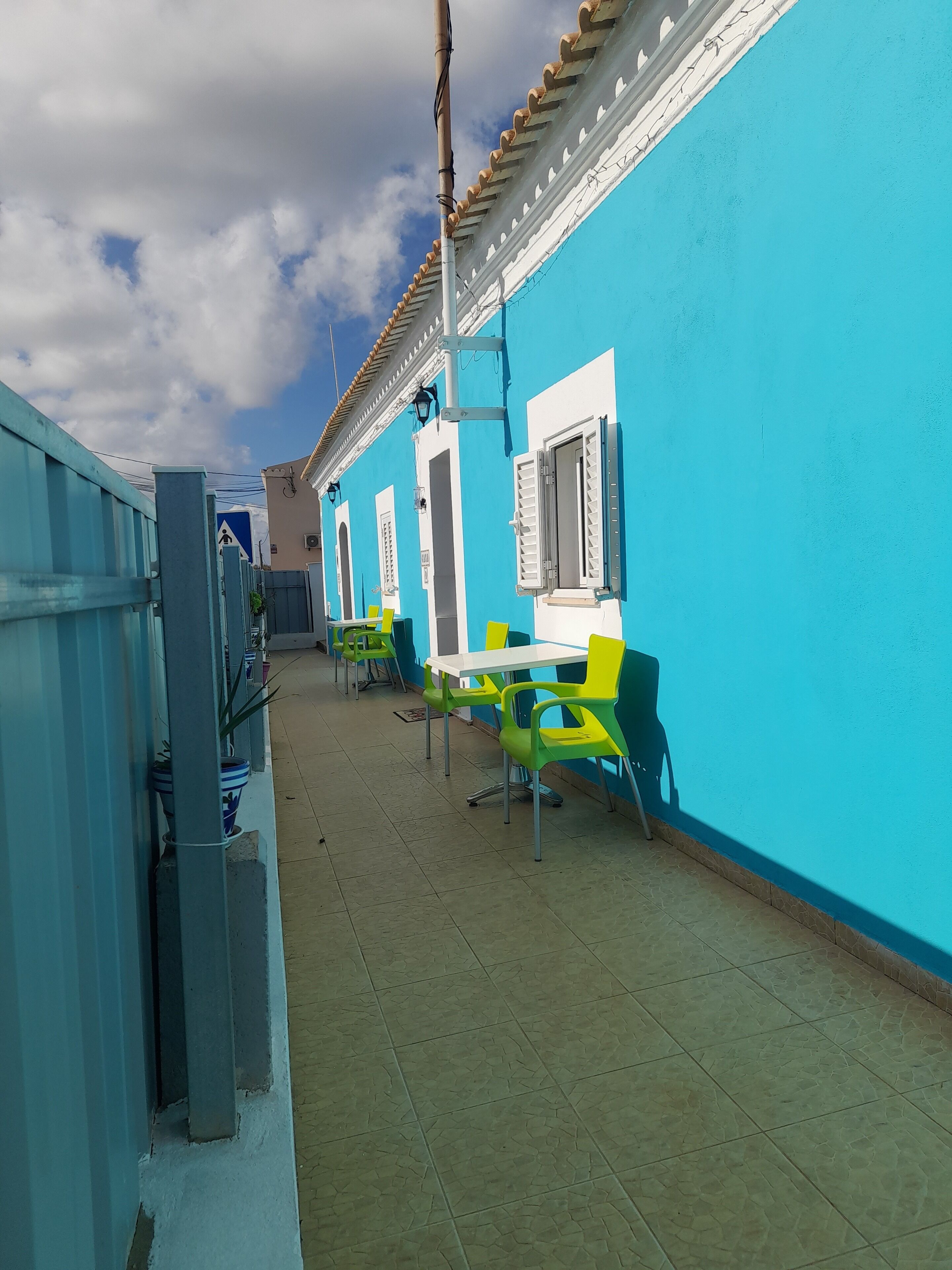 Un pasillo con paredes azules, puertas blancas y sillas verdes.