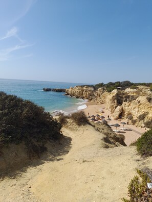 A coastal beach with rocky cliffs, a sandy path, and beach umbrellas. - Studio in Gale, Albufeira (Albufeira)