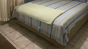 Una camera da letto con un letto, tende, una ventola a soffitto e un quadro appeso al muro.