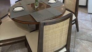 Una cucina moderna con mobili bianchi, un forno a microonde e un lavello. C'è un tavolo da pranzo con un vaso di fiori e un piatto.