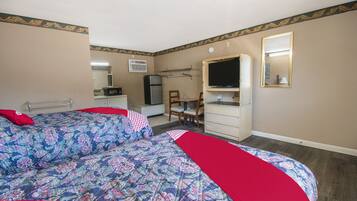 A hotel room with two beds, a desk, a chair, a television, and a dresser.