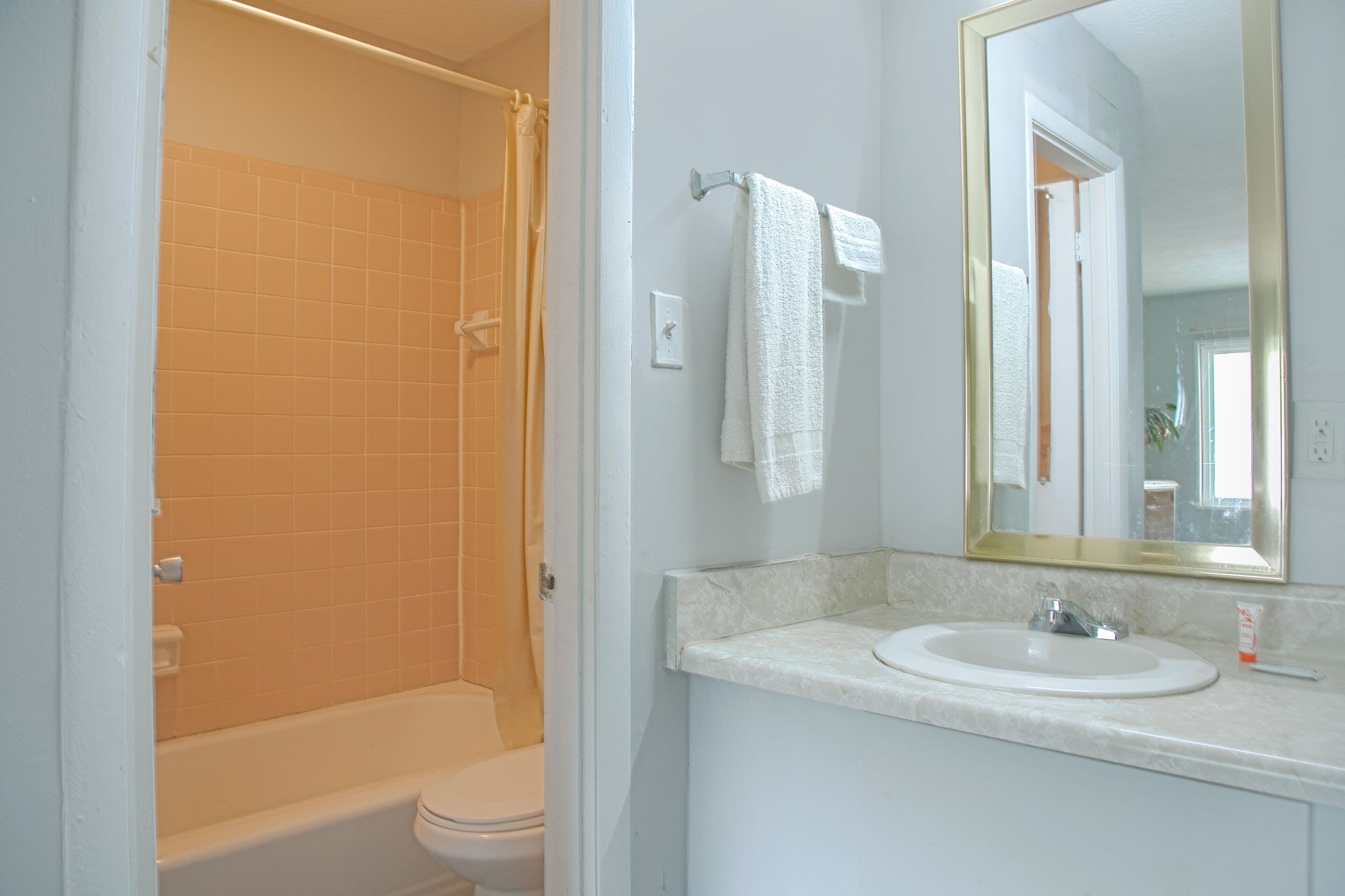 A bathroom with a bathtub, toilet, sink, and a mirror.