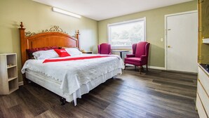A neatly arranged bedroom with a wooden bed, a red chair, and a window with blinds. - OYO Hotel Calhoun, GA I-75 (Calhoun)