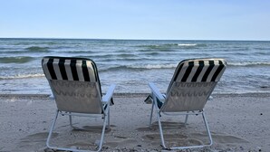 Twee strandstoelen gericht op de zee, met een heldere lucht.