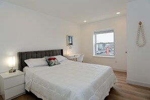 A bedroom with a bed, nightstand, desk, and window.