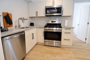 Enjoy cooking in this well-lit kitchen with stainless steel appliances, white cabinetry, and a wooden countertop.