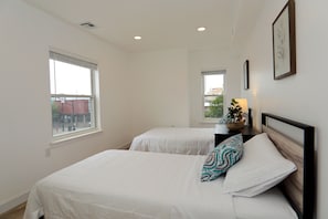 Two single beds with white bedding and matching headboards, each adorned with a decorative pillow, offer a comfortable retreat.