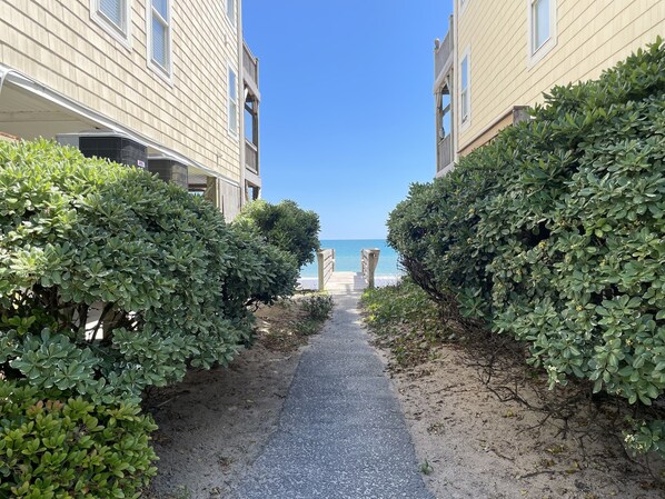 A pathway leading to a beach with buildings on either side.