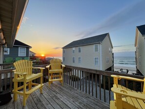 Guests can enjoy a serene ocean view from the deck, featuring two Adirondack chairs.