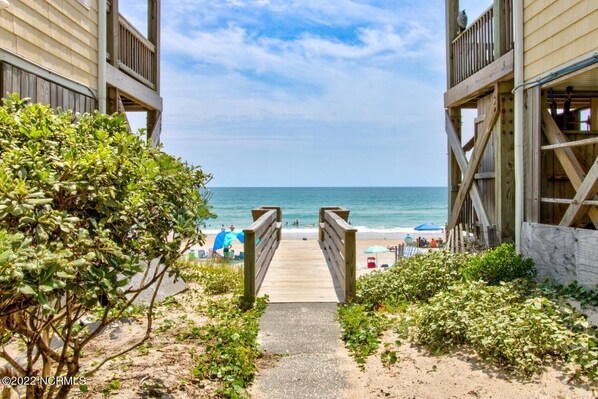 Walk along the boardwalk to the beach, surrounded by lush greenery and ocean views.