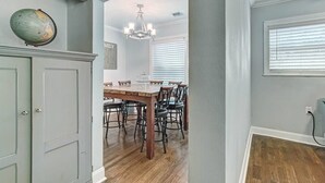 A dining area with a wooden table and chairs, a globe on the wall, and a chandelier.