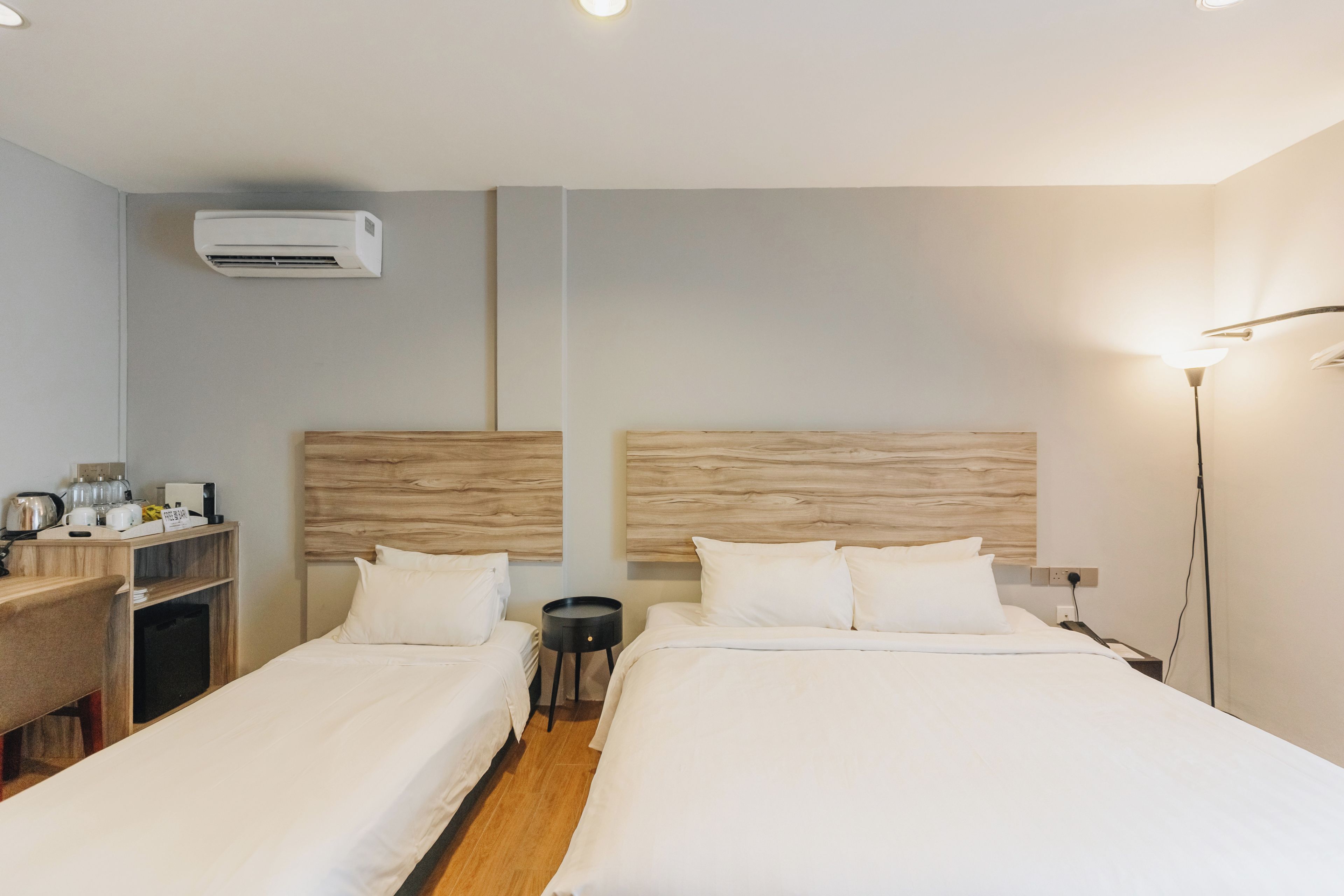Ein Hotelzimmer mit zwei Betten, einem Schreibtisch, einem Stuhl, einer Lampe und einer Klimaanlage.