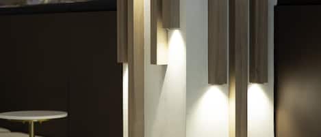 A modern interior with minimalist design, featuring a counter with a stool, a wall-mounted light fixture, and a clean, uncluttered space.
