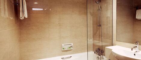 Un baño moderno con ducha acristalada, una bañera blanca y un lavamanos con espejo.