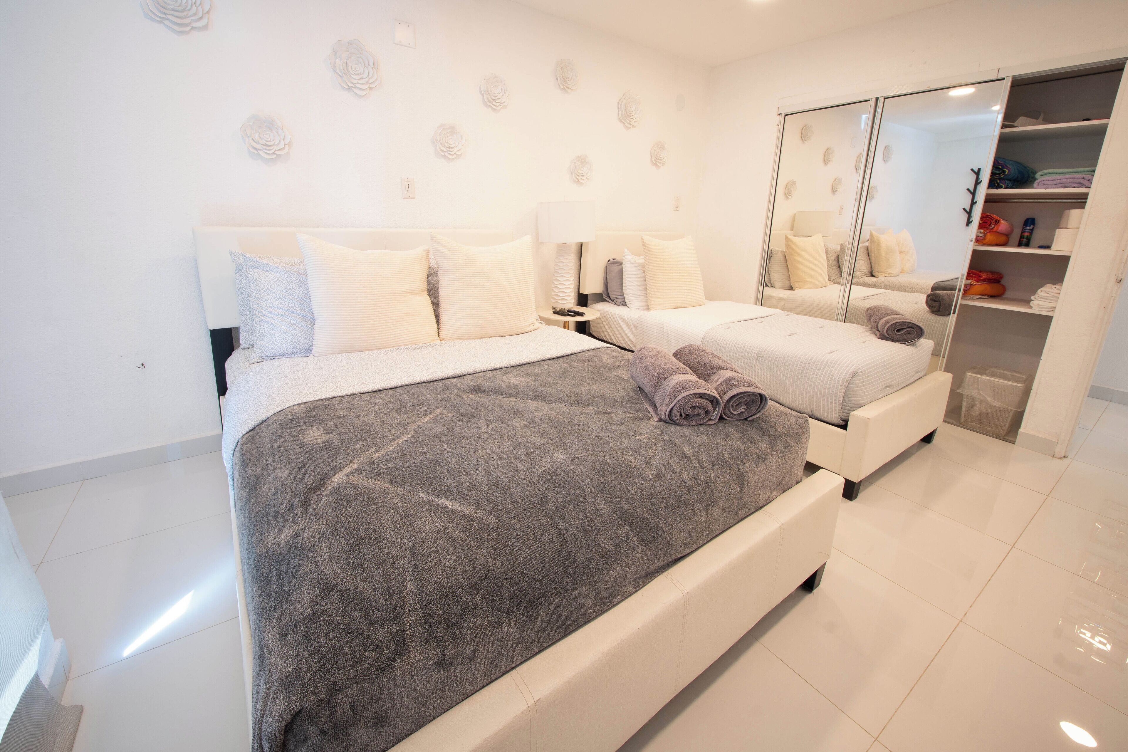 Een moderne slaapkamer met een groot bed, een kledingkast en een spiegel.