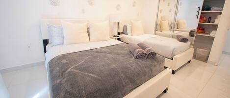 Een moderne slaapkamer met een groot bed, een kledingkast en een spiegel.