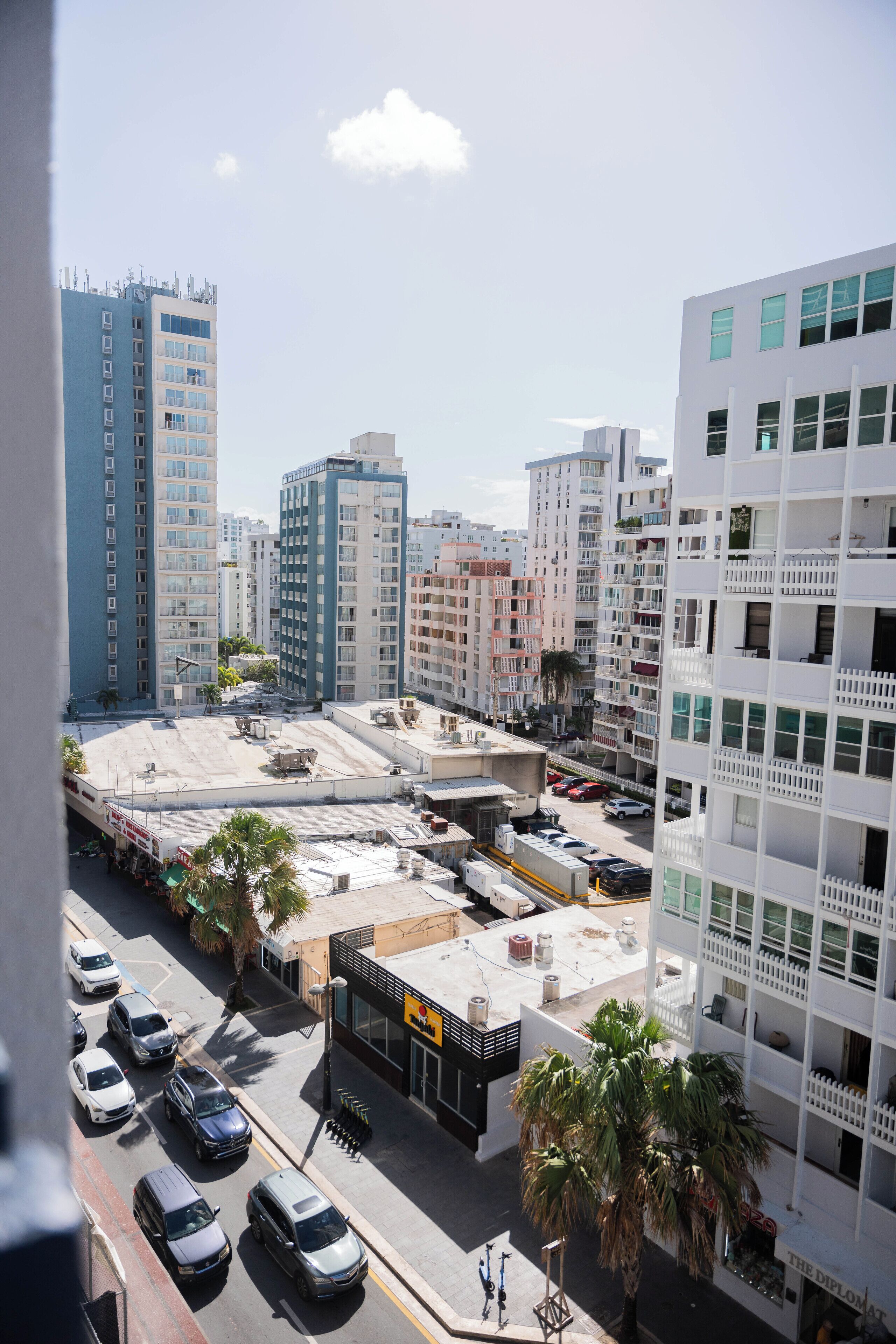 A high-rise building with multiple floors, a parking lot, and several parked cars.