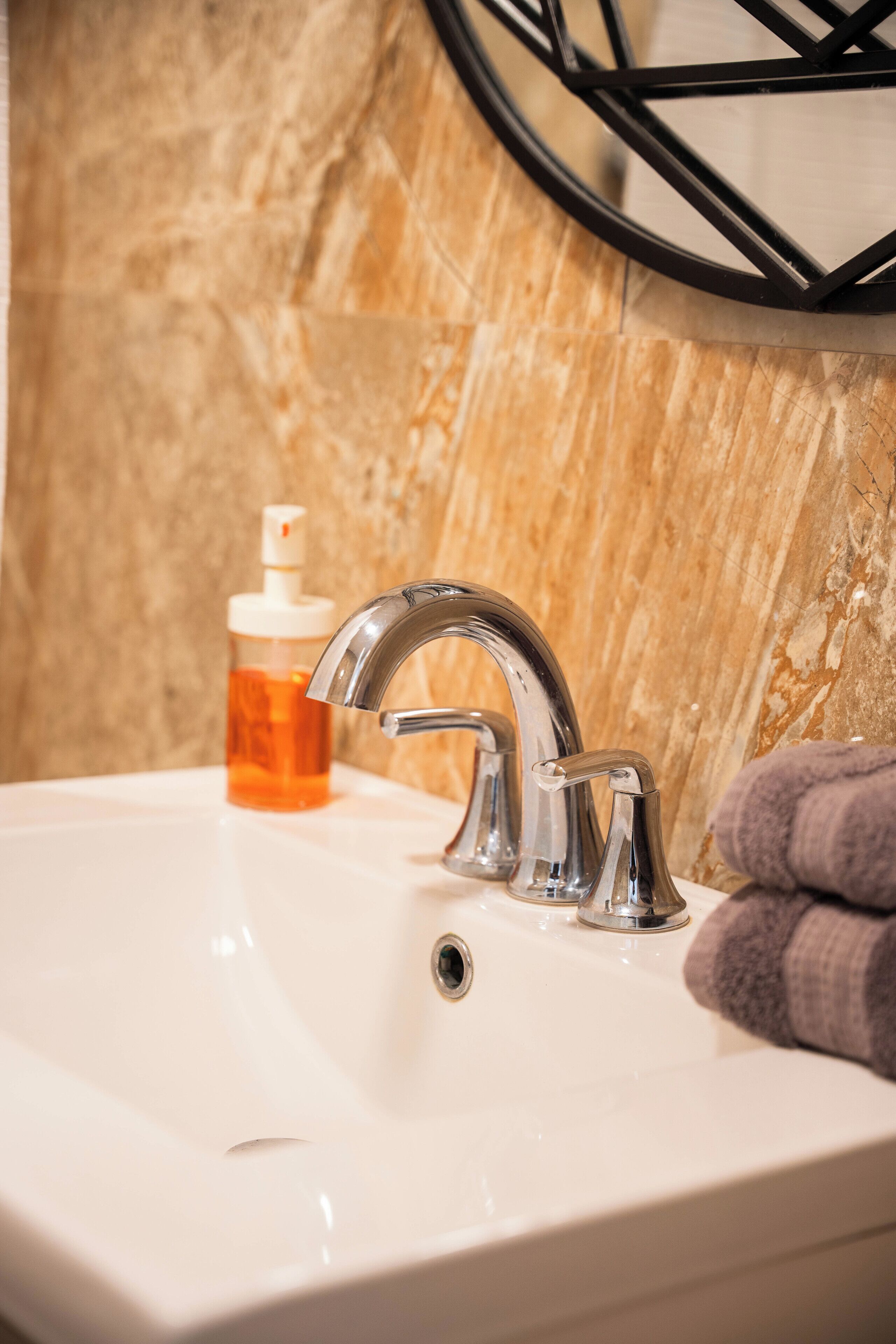 A bathroom sink with a modern faucet, a soap dispenser, and a towel.