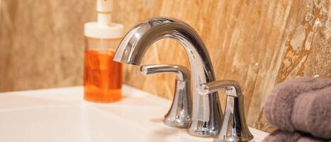 A bathroom sink with a modern faucet, a soap dispenser, and a towel.