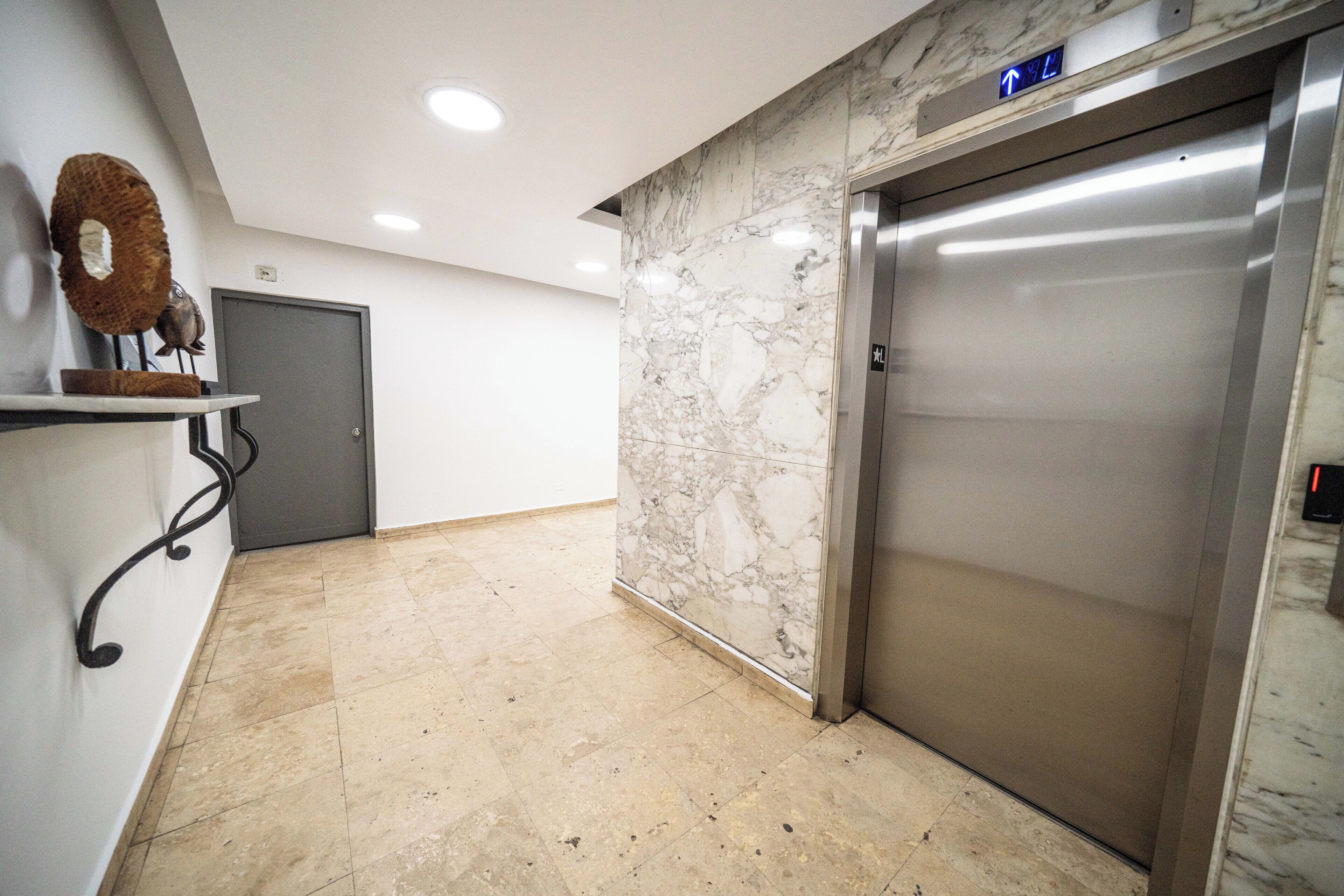 A marble wall, an elevator, and a door in a hallway.