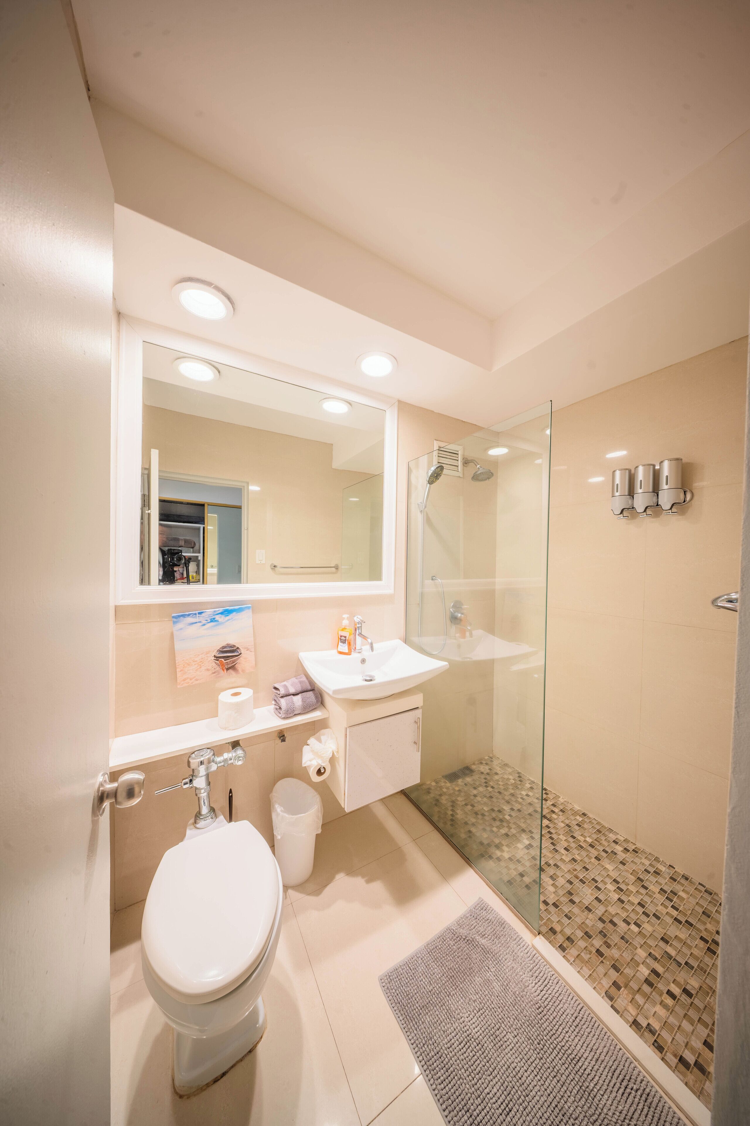 Een moderne badkamer met een douchecabine van glas, een witte wastafel en een toilet.