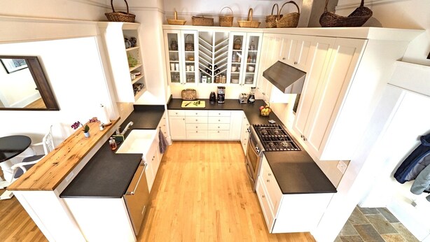 A compact kitchen with white cabinetry, a black countertop, and a wooden floor. - Deluxe Downtown Bungalow - fenced in yard, pet friendly. (Brevard)