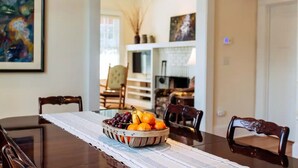A dining table with a fruit bowl in the center, surrounded by chairs. - Deluxe Downtown Bungalow - fenced in yard, pet friendly. (Brevard)
