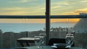 Ein Esstisch mit Blick auf das Meer und die Skyline bei Sonnenuntergang.