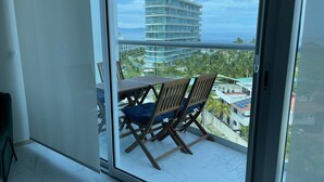 Ein Balkon mit Tisch und Stühlen mit Blick auf ein Gebäude und Palmen.
