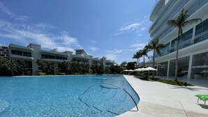Ein Schwimmbad mit klarem, blauem Wasser, umgeben von einem modernen Gebäude mit großen Fenstern und einer flachen Dachkonstruktion.