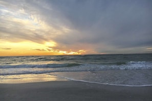 Ein Strand mit Wellen und einem Sonnenuntergang.