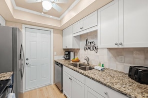 A kitchen with white cabinets, a granite countertop, a coffee maker, and a toaster.