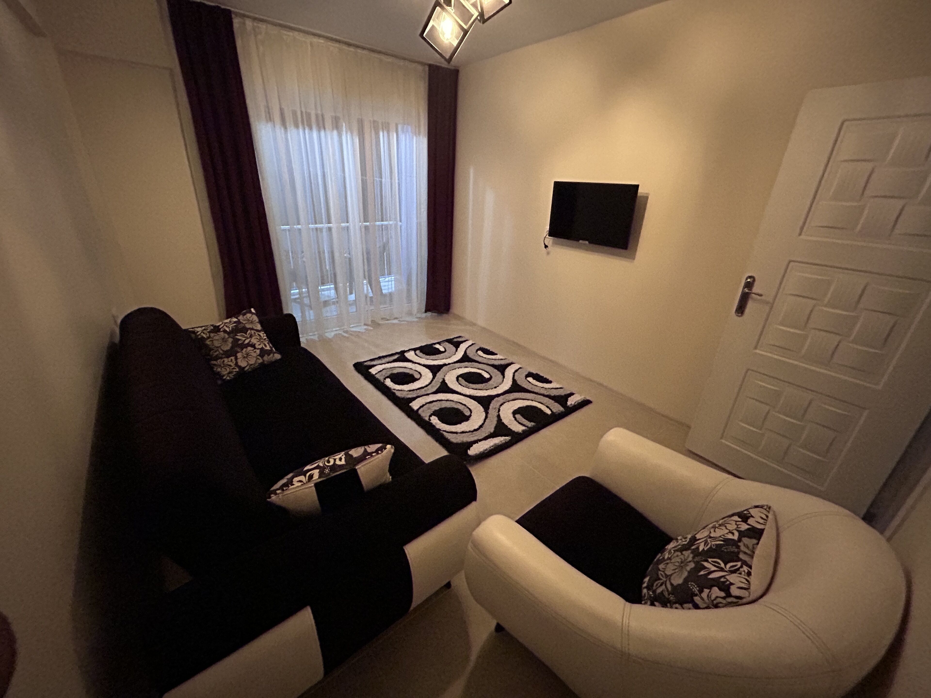 Un salón con sofá, sillón y alfombra estampada.