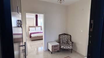 Una habitación con una cama, una silla, una mesita y un tapete rojo.