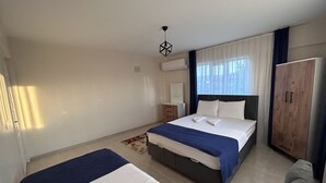 A modern hotel room with a large bed, a smaller bed, a wardrobe, and a bedside table. - The Titanic House (Denizli)