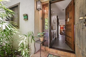 Enter a warm and inviting space through the traditional door, where a potted plant adds a touch of greenery to the interior hallway with a wooden floor and staircase.