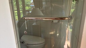 A bathroom with a glass shower enclosure, a toilet, and a checkered floor.