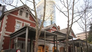 A traditional brick building with a modern glass tower in the background.