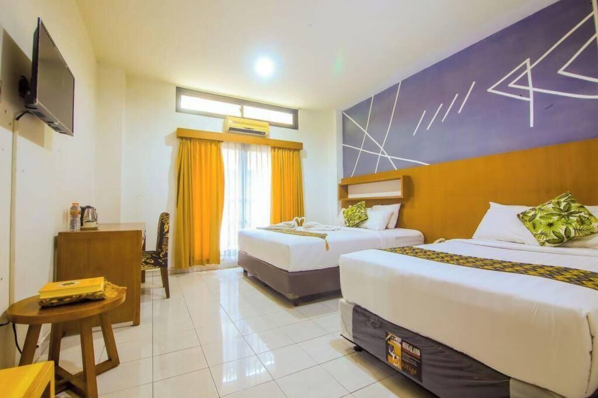 A hotel room with two beds, a TV, a desk, and a chair.