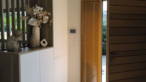 A modern interior with a wooden cabinet, a vase with flowers, and a sliding door.